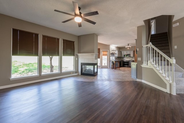 6512 N Fisk Ct, Kansas City, MO 64151 - unfurnished living room with ceiling fan, wood finished floors, baseboards, stairway, and a textured ceiling