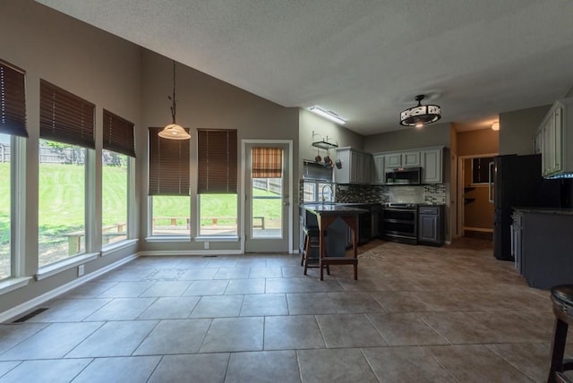 6512 N Fisk Ct, Kansas City, MO 64151 - kitchen with stainless steel appliances, tasteful backsplash, lofted ceiling, light tile patterned floors, and a kitchen breakfast bar
