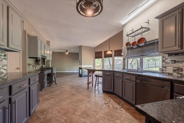 6512 N Fisk Ct, Kansas City, MO 64151 - kitchen with stainless steel dishwasher, lofted ceiling, decorative backsplash, a textured ceiling, and dark stone countertops