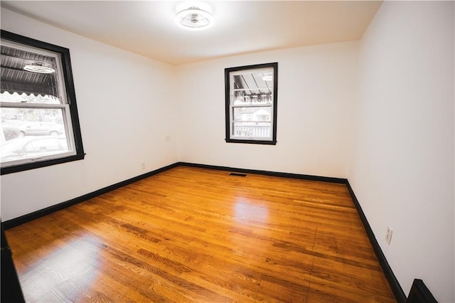 empty room featuring baseboards, wood finished floors, and visible vents