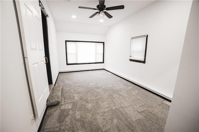 unfurnished bedroom with carpet floors, lofted ceiling, baseboards, ceiling fan, and a barn door