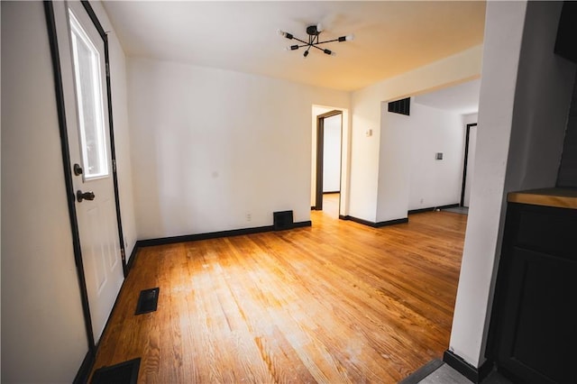 empty room featuring visible vents, baseboards, and light wood-type flooring