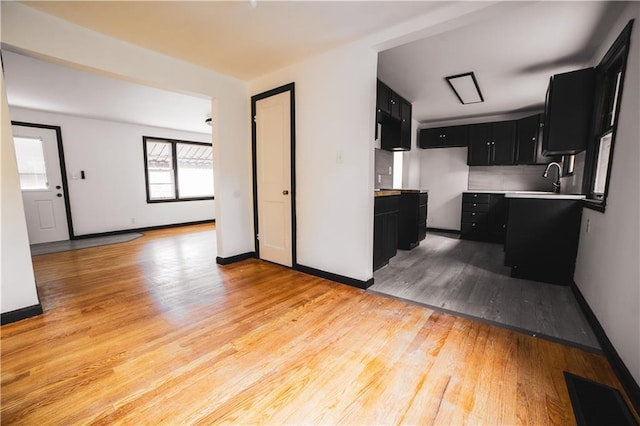 kitchen with dark cabinets, baseboards, and light wood-style floors