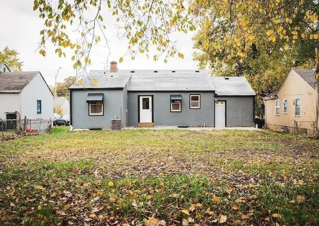 back of house with a lawn, fence, and a chimney