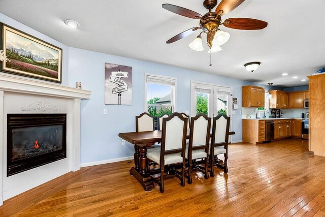 1024 Tamarisk Dr, Leavenworth, KS 66048 - dining room with light wood-type flooring, a ceiling fan, baseboards, and a glass covered fireplace