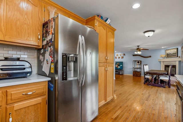 1024 Tamarisk Dr, Leavenworth, KS 66048 - kitchen with stainless steel fridge, tasteful backsplash, ceiling fan, light countertops, and light wood-type flooring