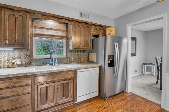 kitchen featuring white dishwasher, stainless steel fridge with ice dispenser, a sink, and light countertops