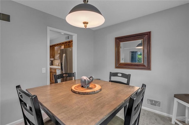 dining area with baseboards and light carpet