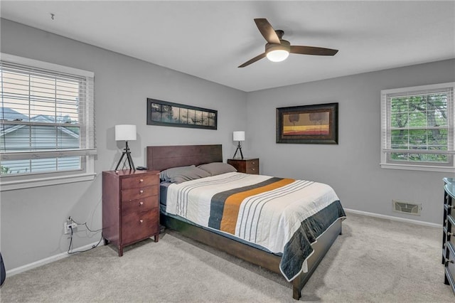 carpeted bedroom featuring multiple windows, baseboards, and ceiling fan