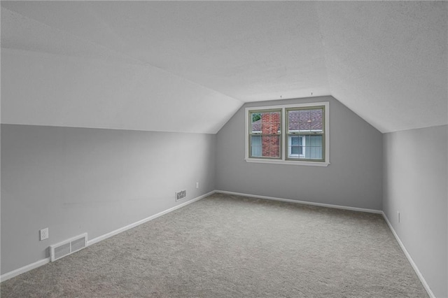 bonus room with carpet flooring, vaulted ceiling, baseboards, and a textured ceiling