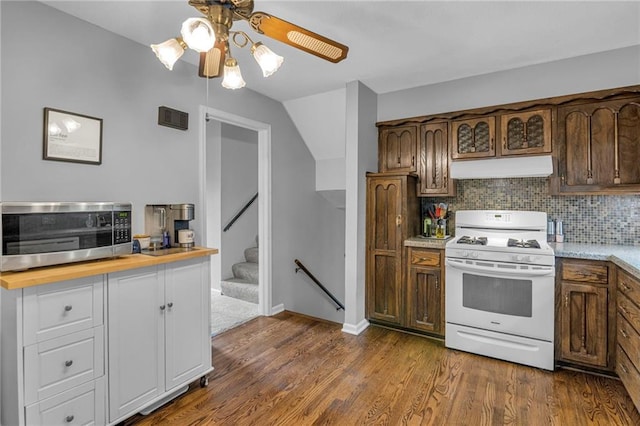 kitchen with white gas range, under cabinet range hood, stainless steel microwave, a ceiling fan, and dark wood-type flooring