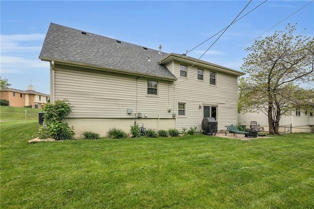 rear view of property featuring roof with shingles, a lawn, a patio, and a fire pit