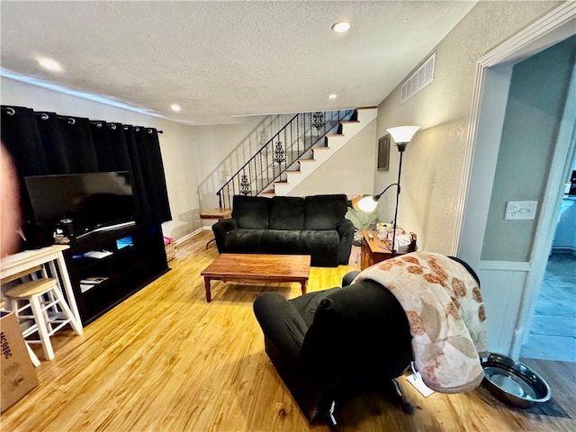 living area with a textured ceiling, stairs, recessed lighting, wood finished floors, and visible vents