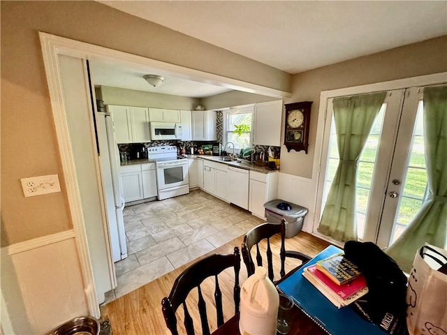 kitchen featuring french doors, wainscoting, a sink, white appliances, and white cabinetry
