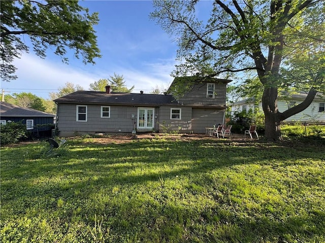 rear view of house featuring a yard, french doors, and a chimney