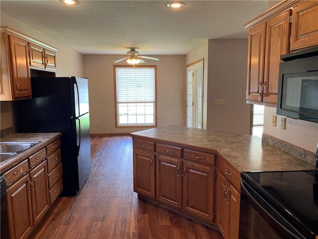 1019 S Hugh St, Frontenac, KS 66763 - kitchen with black appliances, dark wood finished floors, a peninsula, a ceiling fan, and a textured ceiling