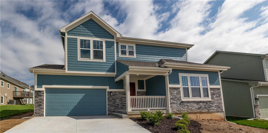 craftsman house featuring covered porch, an attached garage, driveway, and stone siding