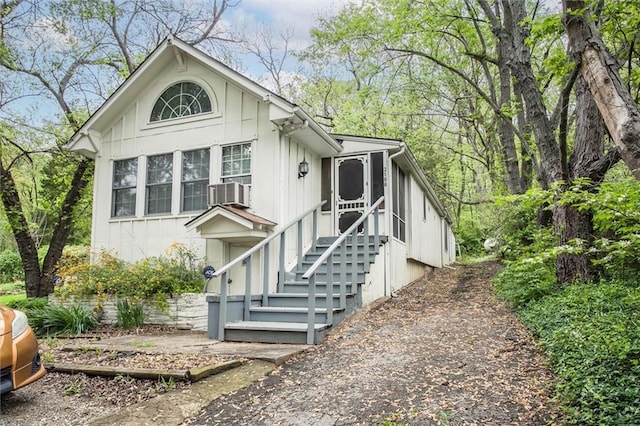 view of front of property with board and batten siding, a sunroom, and cooling unit