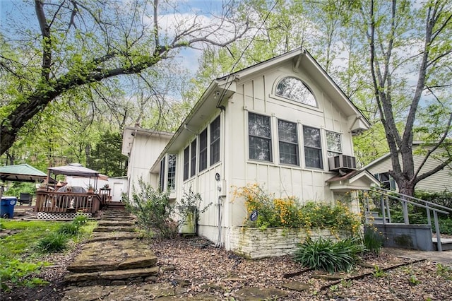 view of side of property featuring central air condition unit, board and batten siding, a wooden deck, and a gazebo