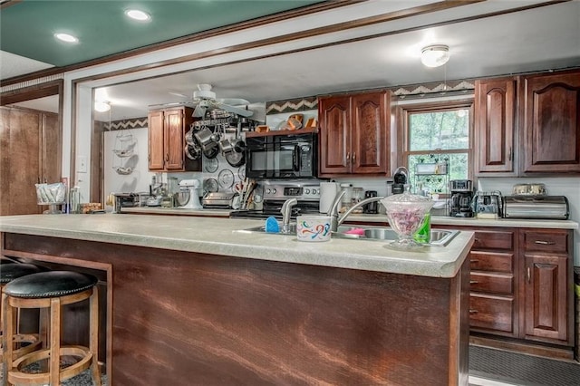 kitchen featuring stainless steel range with electric cooktop, black microwave, a sink, light countertops, and a ceiling fan