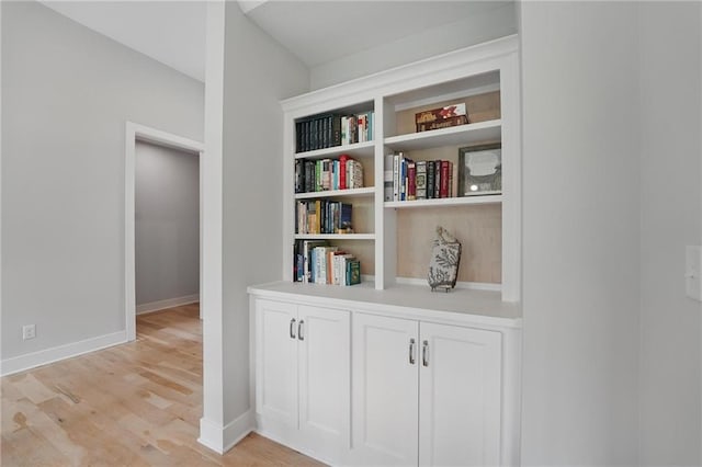 corridor with baseboards and light wood finished floors