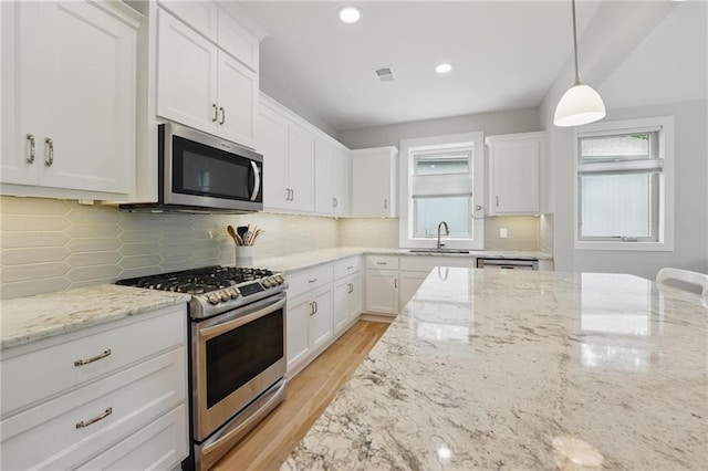 kitchen with plenty of natural light, a sink, white cabinets, and stainless steel appliances