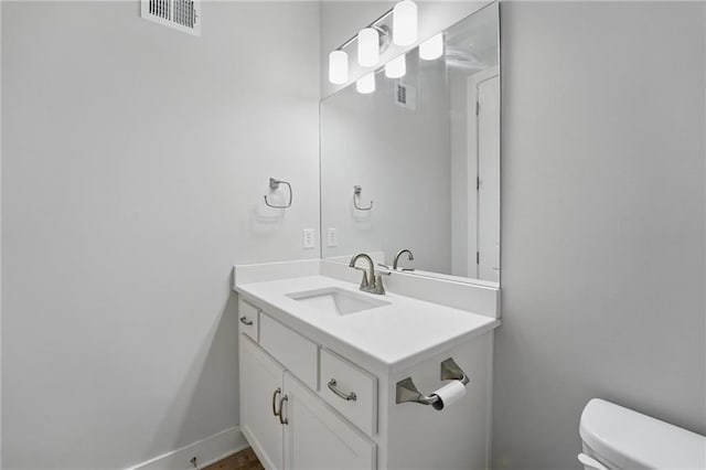 bathroom featuring vanity, baseboards, toilet, and visible vents