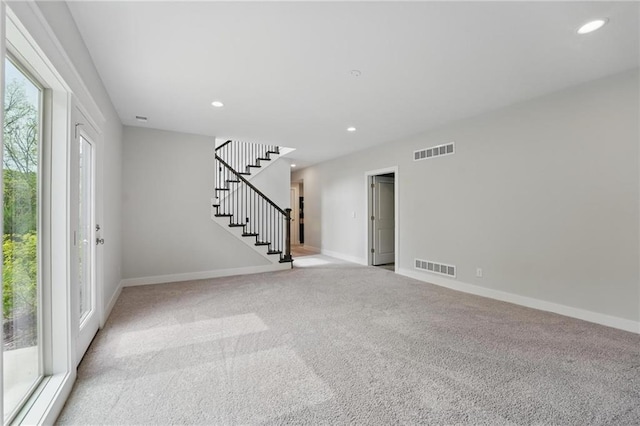 spare room with stairway, carpet flooring, and visible vents