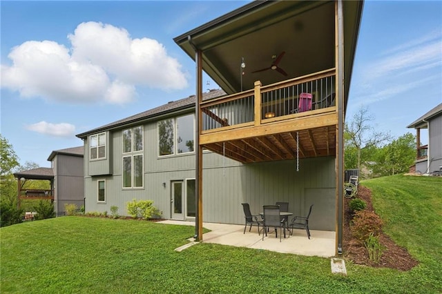 back of property with a lawn, a wooden deck, ceiling fan, and a patio area