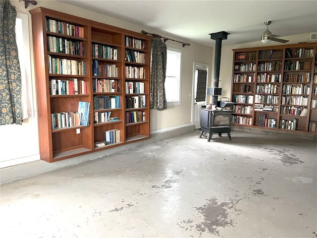 657 N 400th Rd, Overbrook, KS 66524 - sitting room featuring a wood stove, bookshelves, unfinished concrete floors, and a ceiling fan
