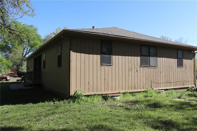 view of property exterior with a lawn and roof with shingles