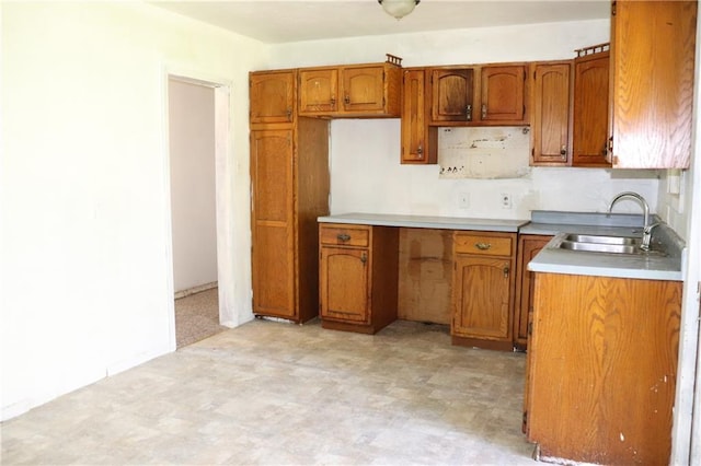 kitchen with a sink, light floors, brown cabinets, and light countertops