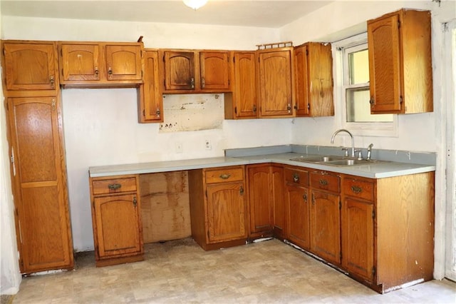 kitchen featuring brown cabinets, light countertops, a sink, and light floors
