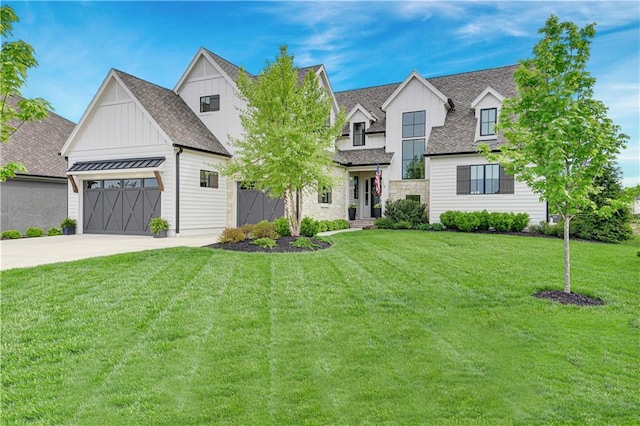 view of front of house with a shingled roof, stone siding, board and batten siding, a front yard, and concrete driveway