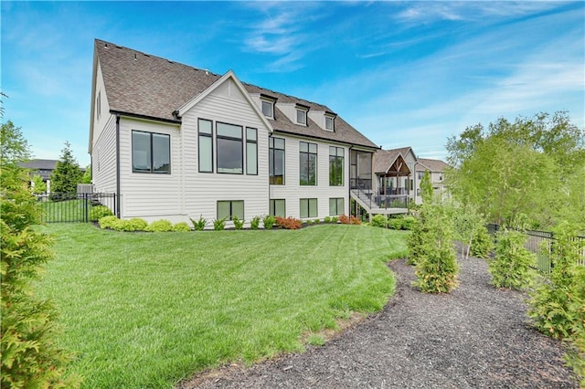back of house with a shingled roof, a fenced backyard, and a yard