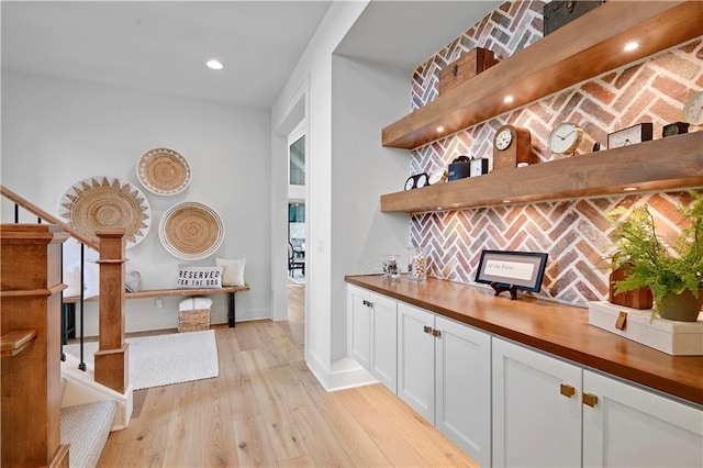 bar featuring light wood-style floors, recessed lighting, baseboards, and stairs