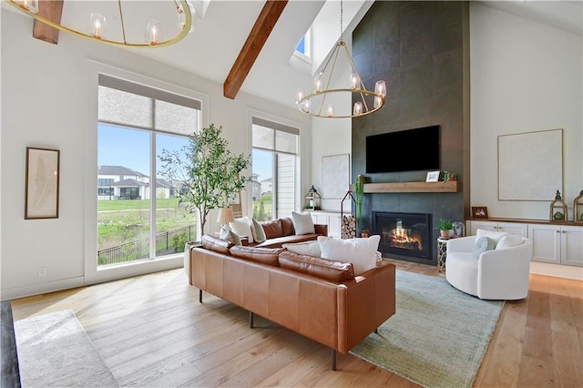 living area with an inviting chandelier, light wood-style flooring, a fireplace, and high vaulted ceiling