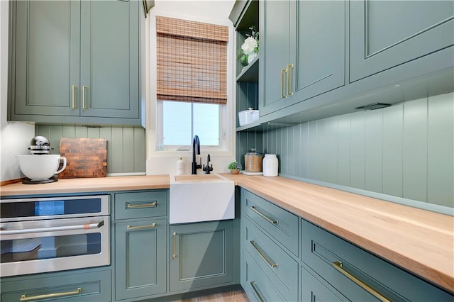 kitchen with open shelves, a sink, wood counters, and oven