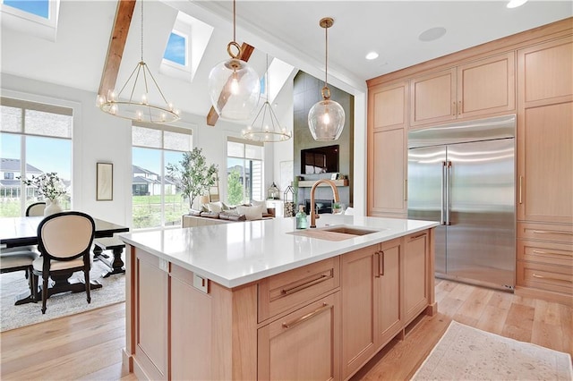 kitchen featuring an inviting chandelier, built in fridge, a sink, and light wood finished floors