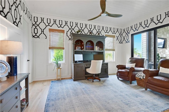 office area featuring a decorative wall, a ceiling fan, and wood finished floors