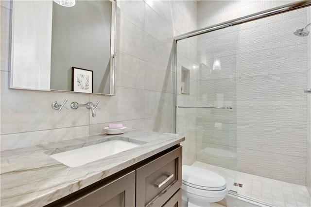 bathroom with vanity, tile walls, toilet, and a shower stall