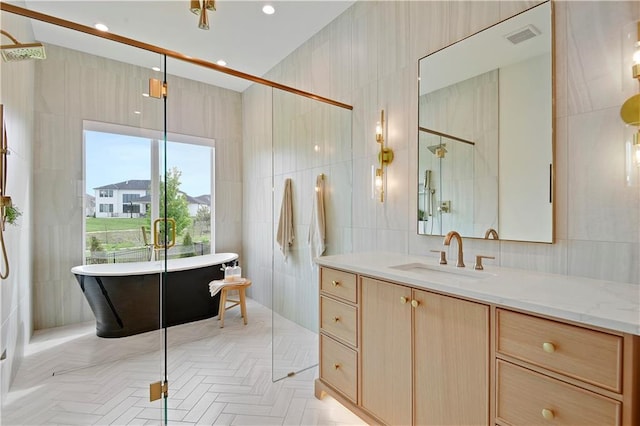 bathroom featuring visible vents, tile walls, a shower with shower door, vanity, and a soaking tub