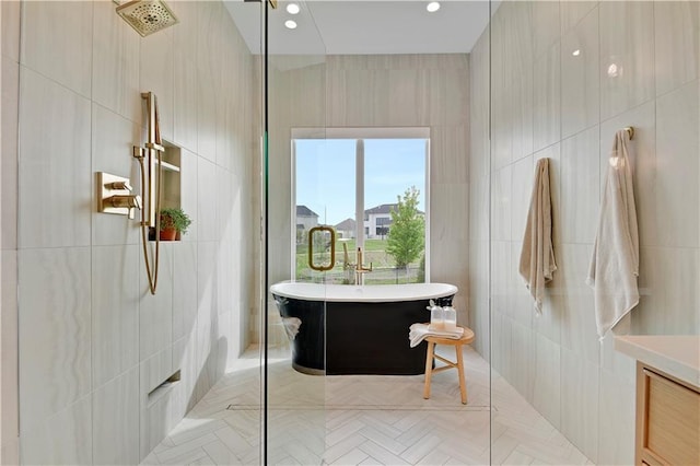 bathroom featuring a freestanding bath, a walk in shower, recessed lighting, and tile walls