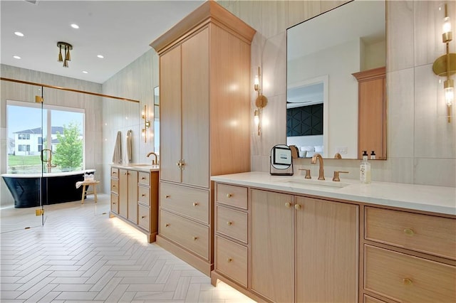 bathroom featuring recessed lighting, a sink, a freestanding bath, and two vanities