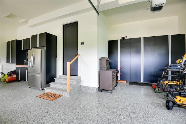 garage featuring stainless steel refrigerator with ice dispenser and a garage door opener