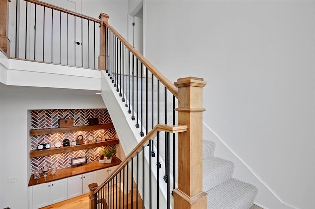 stairs featuring a towering ceiling and wood finished floors
