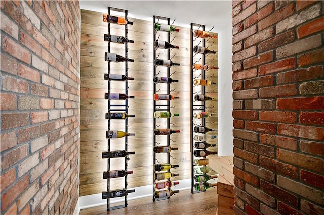 wine room featuring brick wall and wood finished floors