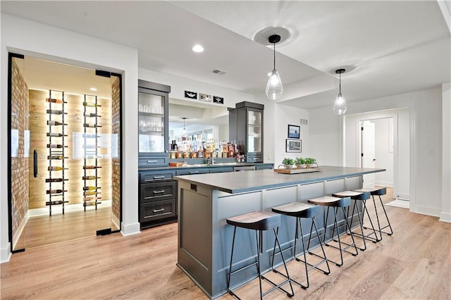 bar featuring pendant lighting, baseboards, light wood finished floors, and visible vents