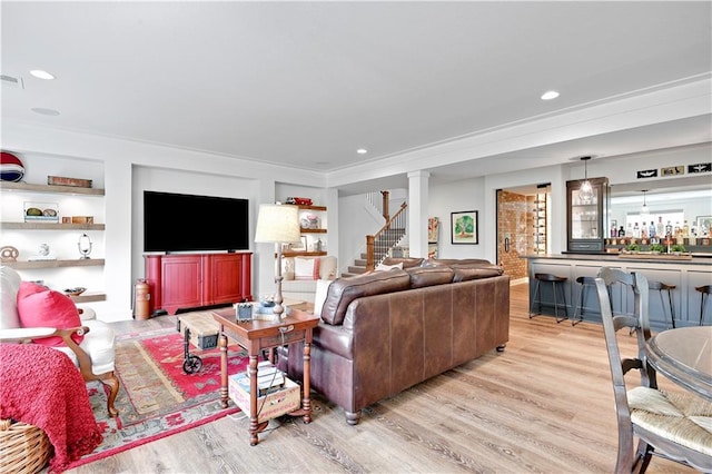 living area featuring crown molding, visible vents, decorative columns, light wood-style floors, and recessed lighting