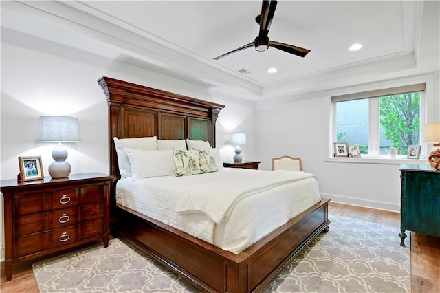 bedroom with a raised ceiling, recessed lighting, baseboards, light wood-type flooring, and visible vents